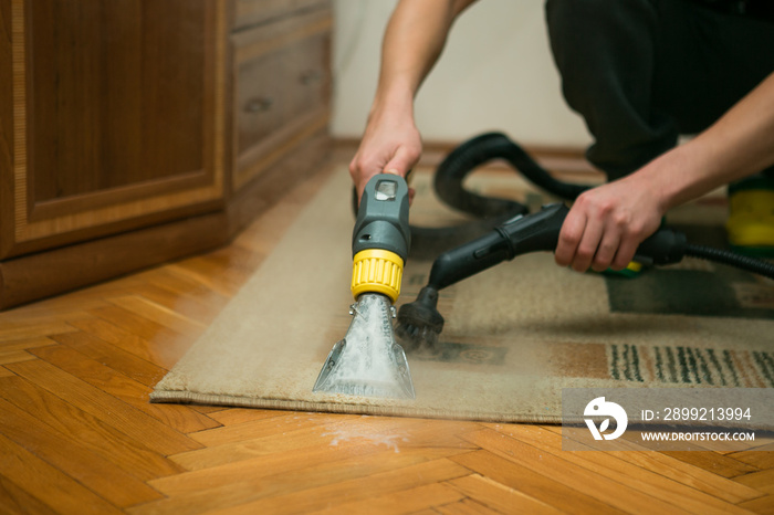 The process of cleaning carpets with a steam vacuum cleaner. An employee of a cleaning company cleans the carpet using steam.