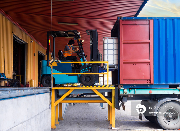 Forklift unstuffing tank of solvent from container to storange in warehouse.