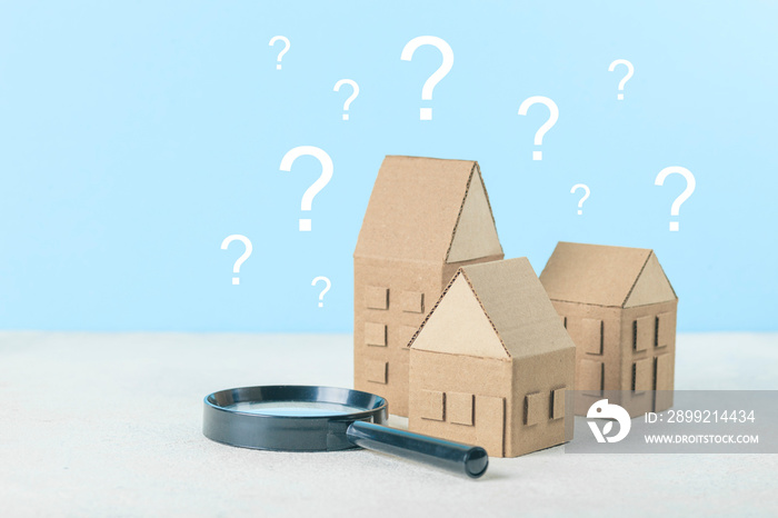 A question on a small house, a magnifying glass examines the building. Assistance in choosing and buying real estate.