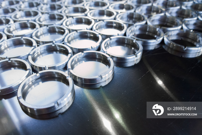 shiny metal rings after turning and milling, silver colored parts on flat steel surface close-up full frame background