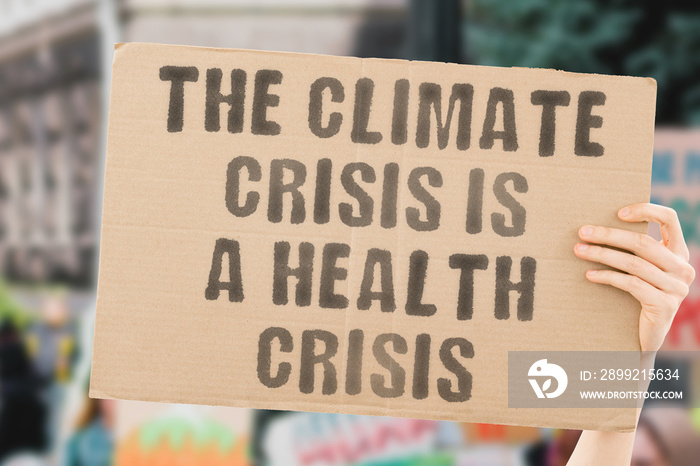 The phrase   The climate crisis is a health crisis   on a banner in men’s hand with blurred background. Responsibility. Sick. Sickness. Temperature. Sustainable environment. Treatment. Ecological.