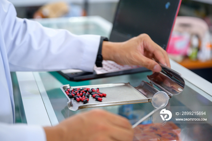 close-up photo of young male pharmacist work in a pharmacy Currently selecting pills and dispensing pills to patients who come to buy pills.