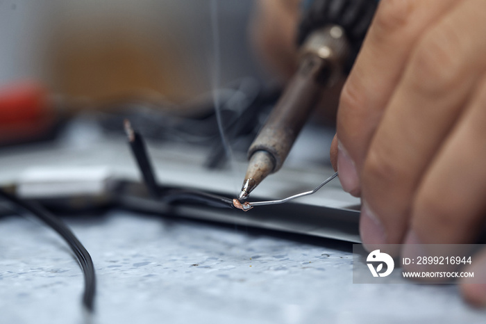 Wires being soldered together with a soldering iron. Melting solder wire on soldering iron tip