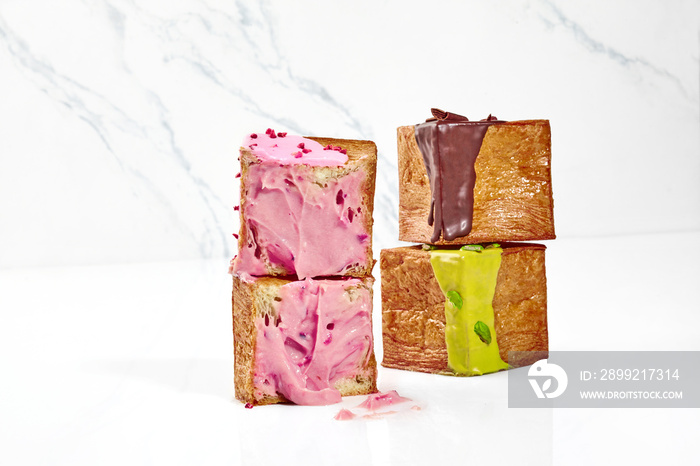 Sliced ​​puff cube croissant with berry cream and two whole cubes with pistachio glaze and chocolate ganache