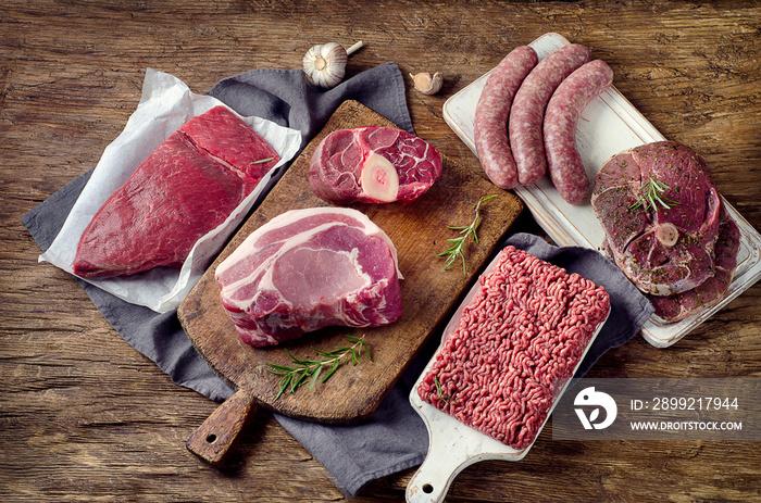 Different types of raw meat on dark wooden background.