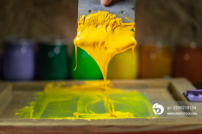 yellow color dripping from hand screen printing during printing tee shirt in tee shirt factory.