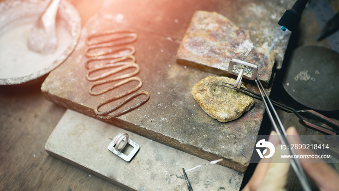 Jeweler at work in jewelry. Desktop for craft jewelry making with professional tools. Close up view of tools. Silver jewelry.