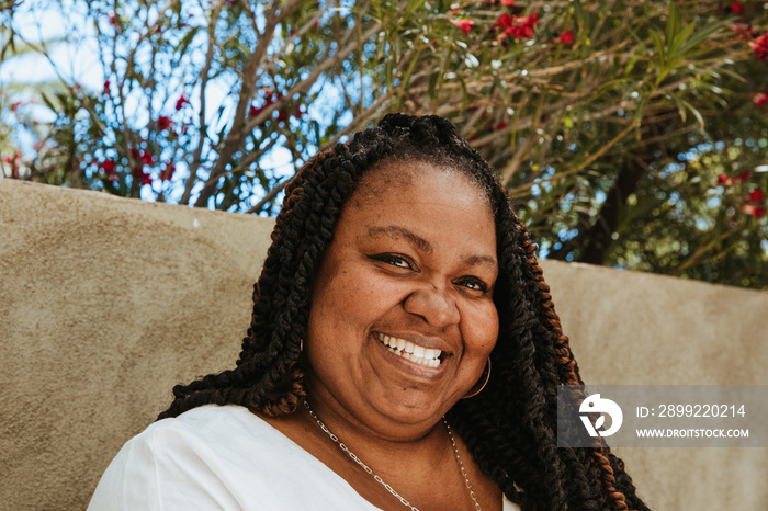 close up plus size afro latinx haitian american woman smiling against textured wall