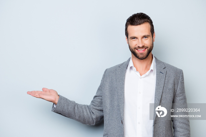 Handsome smiling young man in jacket showing on copyspace with his hand