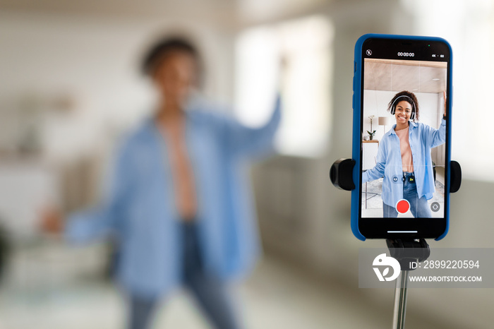 Cheerful black woman filming video on cellphone