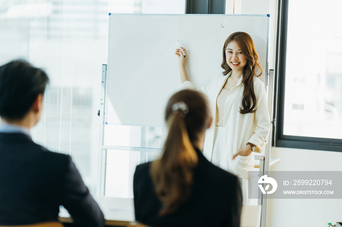 Group of business people discussing and looking at whiteboard in the office