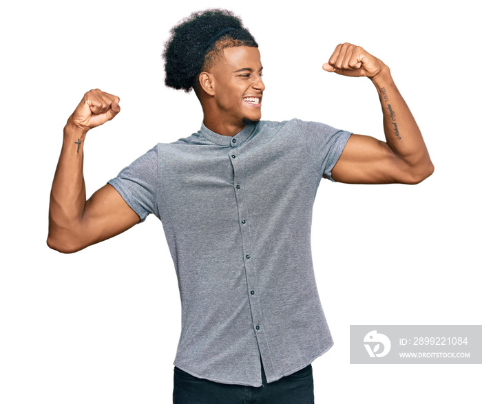 African american man with afro hair wearing casual clothes showing arms muscles smiling proud. fitness concept.