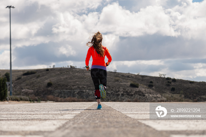 Young woman running on a road outside seen from behind