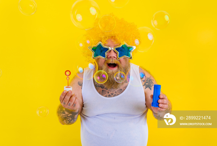 Amazed man with yellow wig in head play with bubbles soap