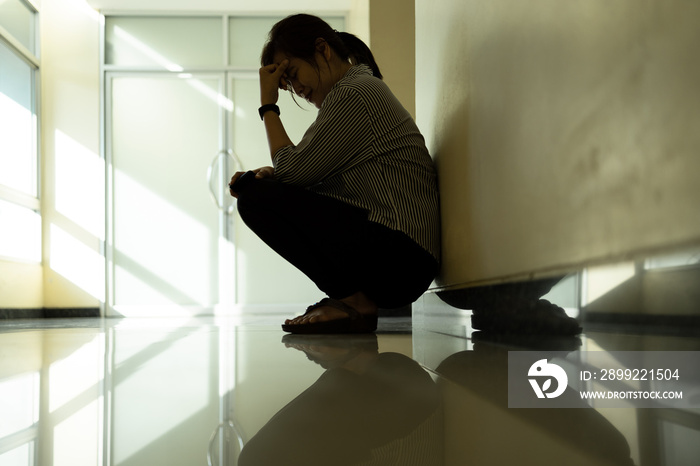 Sad asian woman crying and sitting alone,corridor in hospital,female people waiting  for the doctor in front of the emergency room,feel stressed and worried about her husband about emergency accident