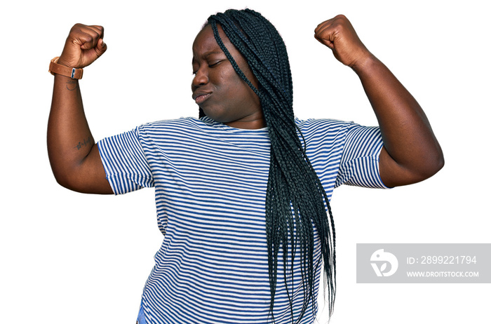 Young black woman with braids wearing casual clothes showing arms muscles smiling proud. fitness concept.