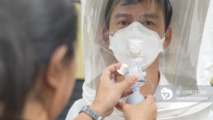 Respirator fit test prepared for COVID-19. Asia man testing repiratory system with N-95 surgical mask to checks properly fits face to wears.