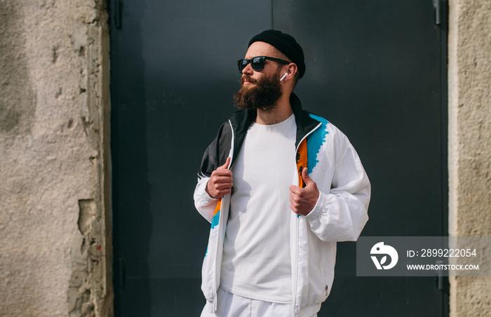 Young bearded hipster guy wearing a vintage tracksuit and white blank t-shirt. Mock-up for print. T-shirt template.