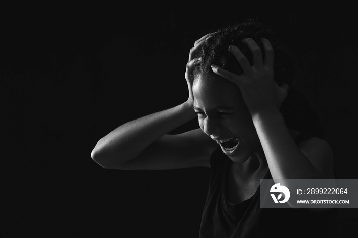 Stressed African-American girl on dark background. Stop racism