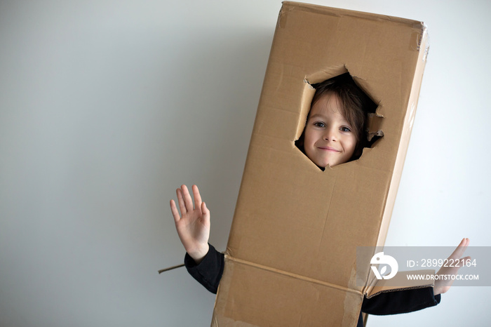 Sweet toddler child, cute blond boy, hiding in cardboard box, looking out