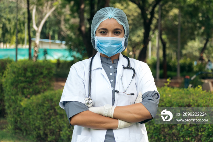 Portrait of confident Indian doctor wear white coat and mask with arms crossed. Professional occupation person during covid-19, concept of medical service In India. Doctor supporting vaccination India