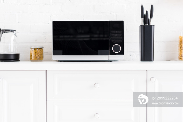 microwave, electric kettle, pasta, knives on surface in kitchen