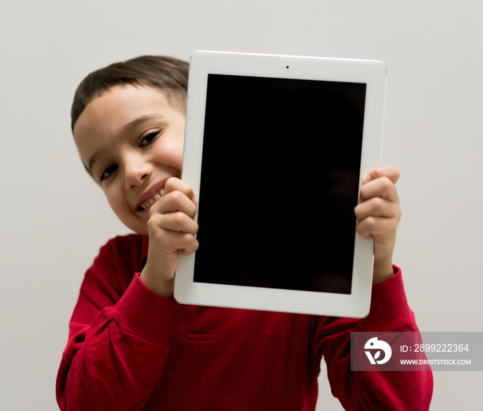 Little cute boy at home holding tablet with copy space