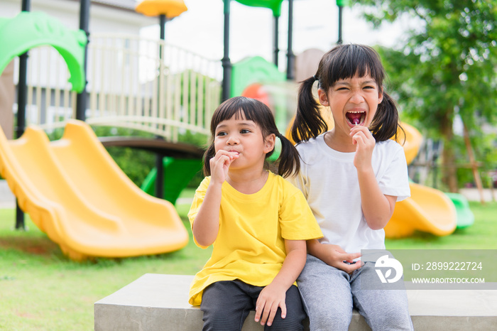 Two kids play and eat lollypops on  playground