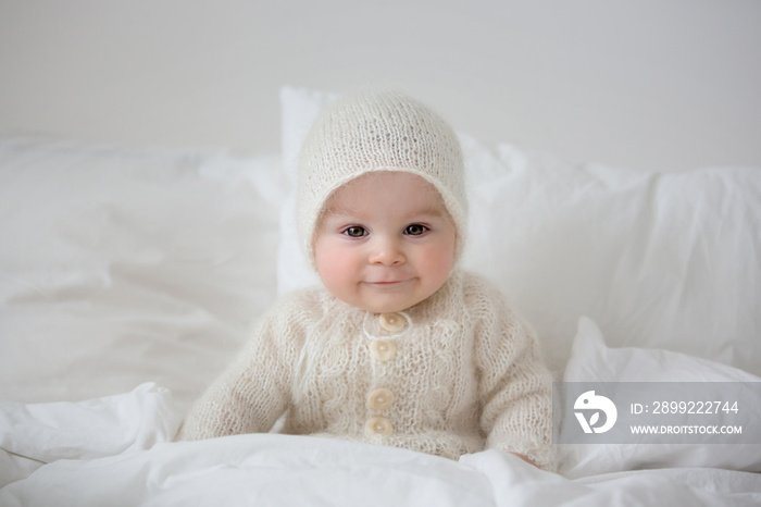 Little cute baby boy, dressed in handmade knitted white teddy bear overall, sleeping