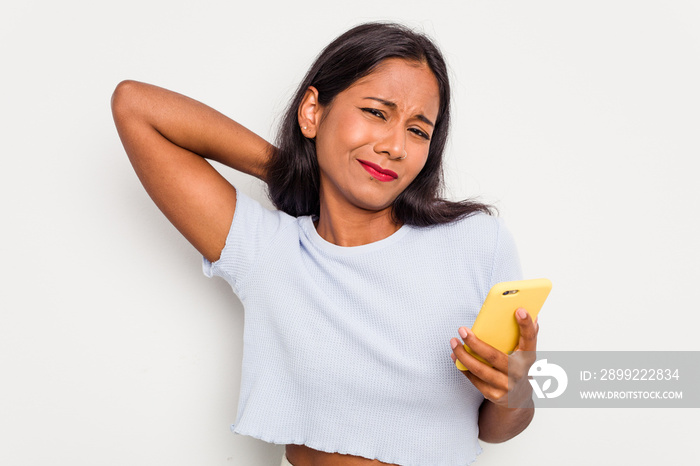 Young indian woman using mobile phone isolated on white background touching back of head, thinking and making a choice.