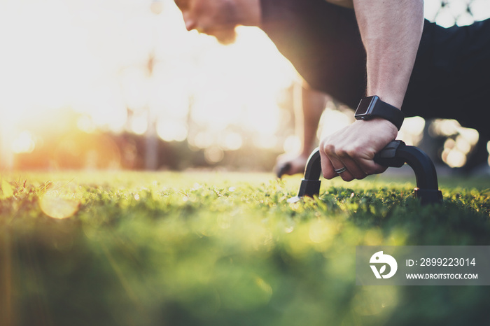 Healthy lifestyle concept.Muscular athlete exercising push up outside in sunny park. Fit shirtless male fitness model in crossfit exercise outdoors.Sport fitness man doing push-ups.Blurred background.