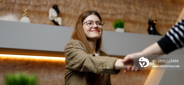 Business handshake of young woman, successful deal. Young smiling trainee girl is being interviewed for a new job.