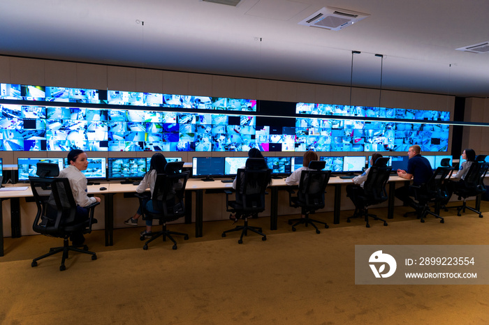 Team of secret agents in uniforms, monitoring cyber, video and communications at the main control data center station.