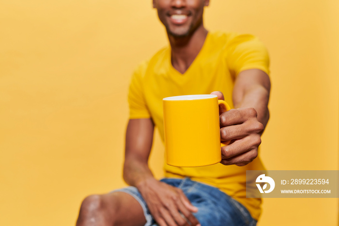 African man sitting and holding a yellow cup