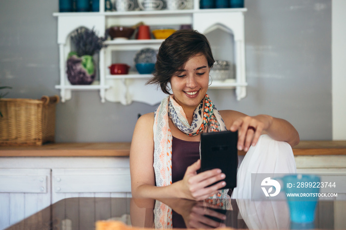 woman drinking coffee and using tablet at her home