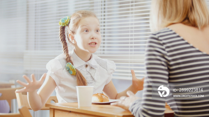 Girl with mommy in cafe - teen explains something for mother