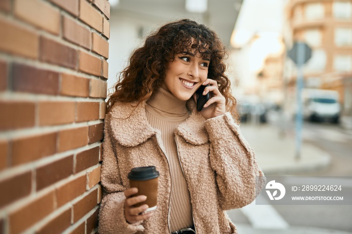 Young hispanic woman smiling happy talking on the smartphone at the city