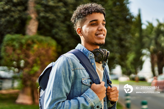 Hispanic young man smiling wearing headphones at the university campus