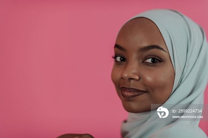 Portrait of young modern muslim afro beauty wearing traditional islamic clothes on plastic pink background. Selective focus