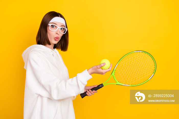 Profile side view portrait of attractive amazed girl fan amateur playing tennis isolated over bright yellow color background