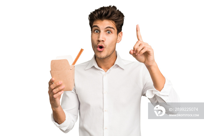 Young caucasian man holding a takeaway of noodles isolated having an idea, inspiration concept.