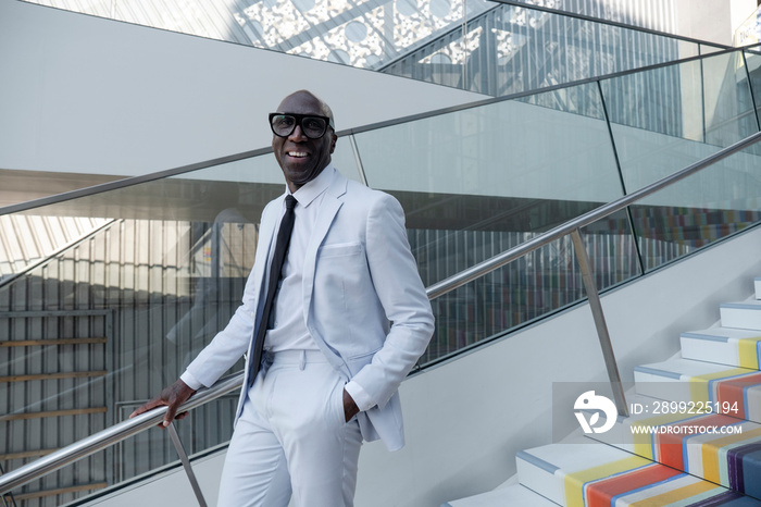 Confident man wearing white suit standing on colorful steps