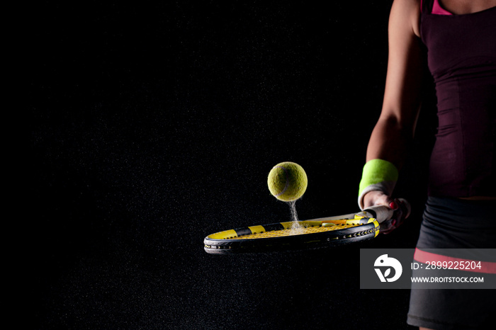 Tennis ball bouncing on racket. Dirt or magnesium dust dots visible in the air. Female player holding racket