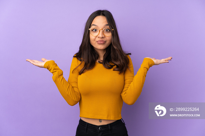 Young mixed race woman isolated on purple background having doubts while raising hands