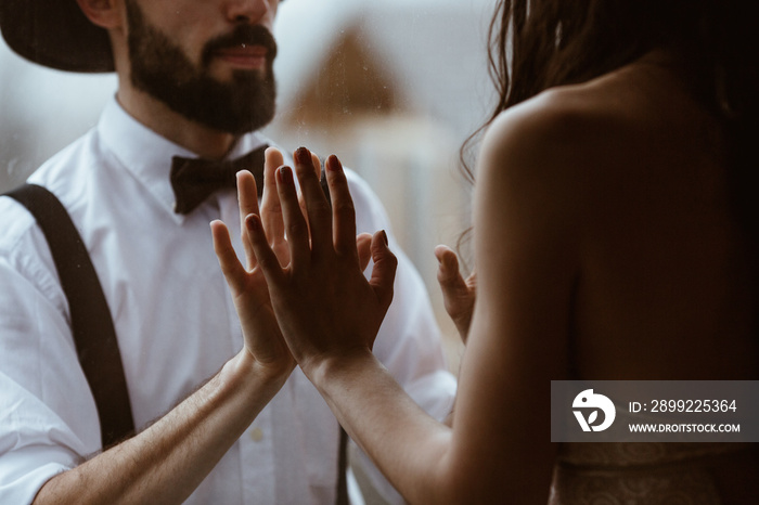 portrait of a stylish wedding couple: Young bearded man in hat and brunette bride in elegant gown wearing a wreath braided in hairstyle