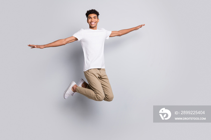 Full size profile photo of brunet optimistic nice guy jump wear white t-shirt pants isolated on grey background