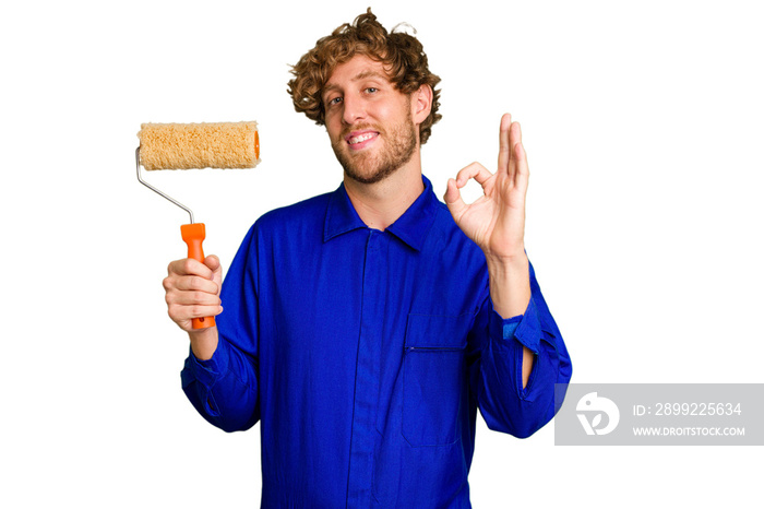 Young painter man holding a roll isolated on white background cheerful and confident showing ok gesture.