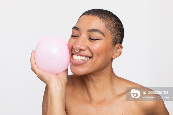 Studio portrait of smiling woman holding pink balloon