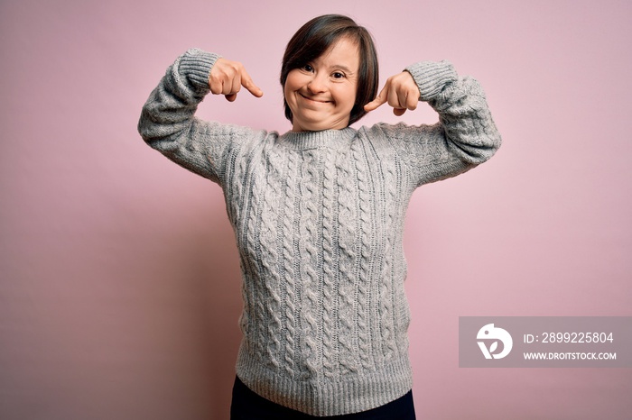 Young down syndrome woman wearing casual sweater over isolated background smiling cheerful showing and pointing with fingers teeth and mouth. Dental health concept.