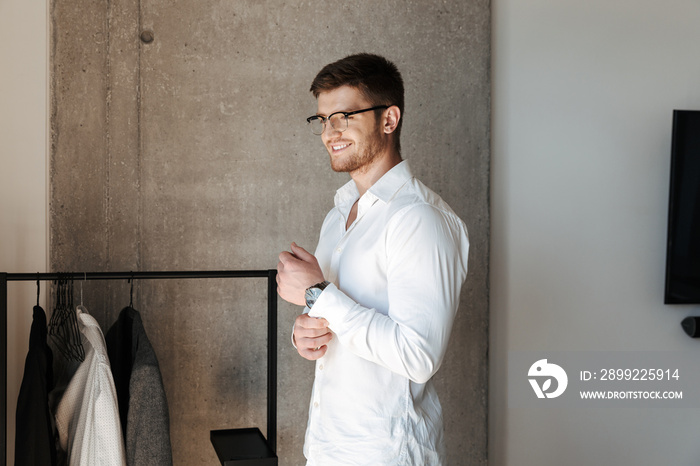 Confident young man putting on white shirt